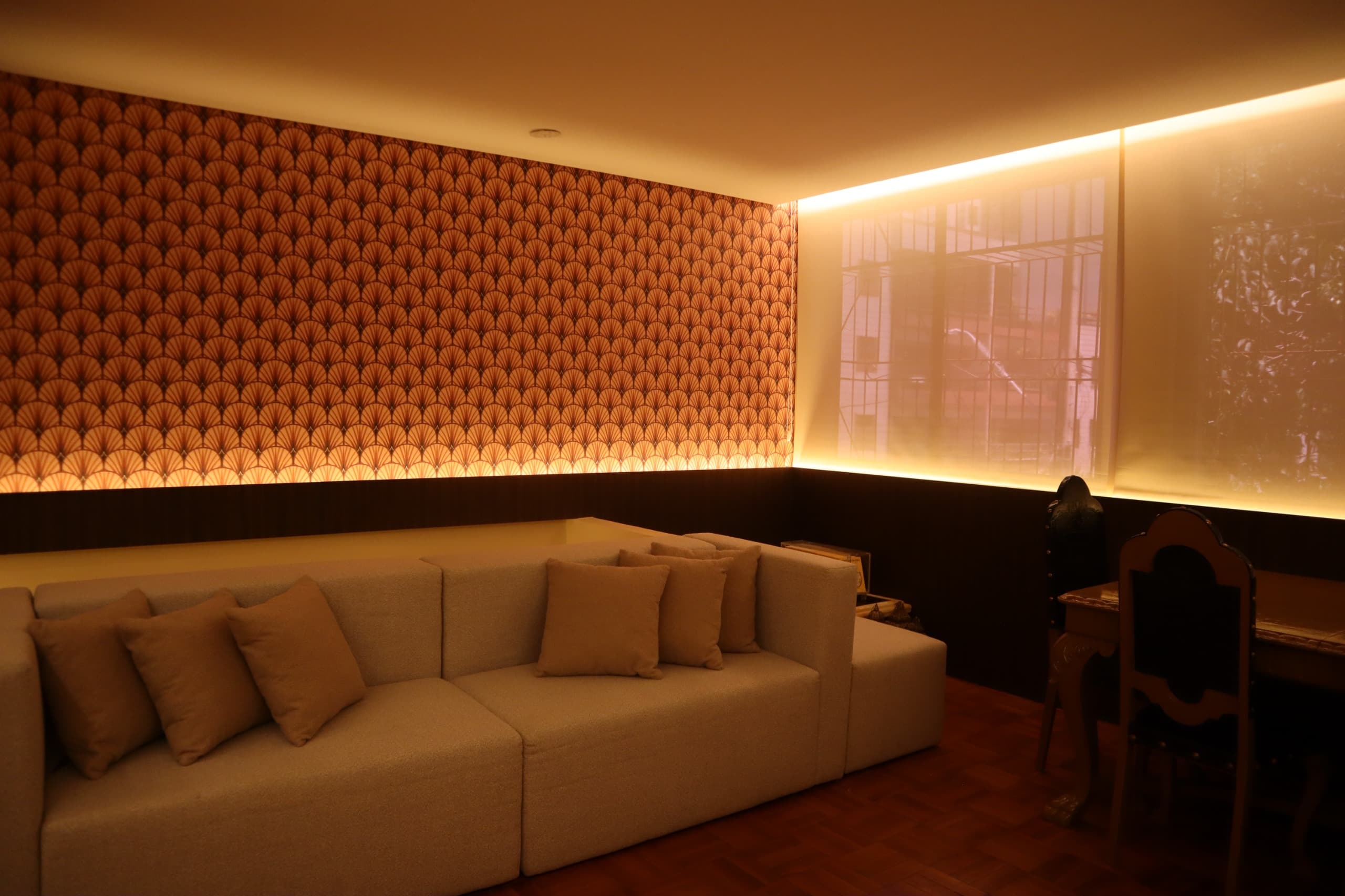 Sala de estar com iluminação indireta, sofá em L e atmosfera acolhedora em projeto da Littore Arquitetos.